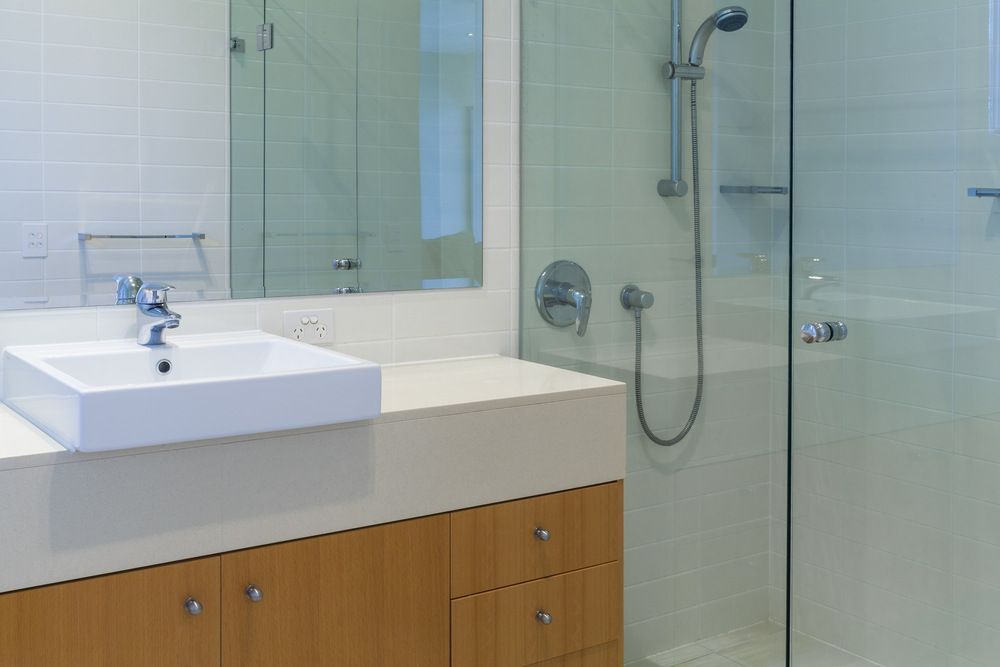 A Bathroom With a Sink, Shower and Mirror — Bruce Smith Cabinets in Bray Park, NSW