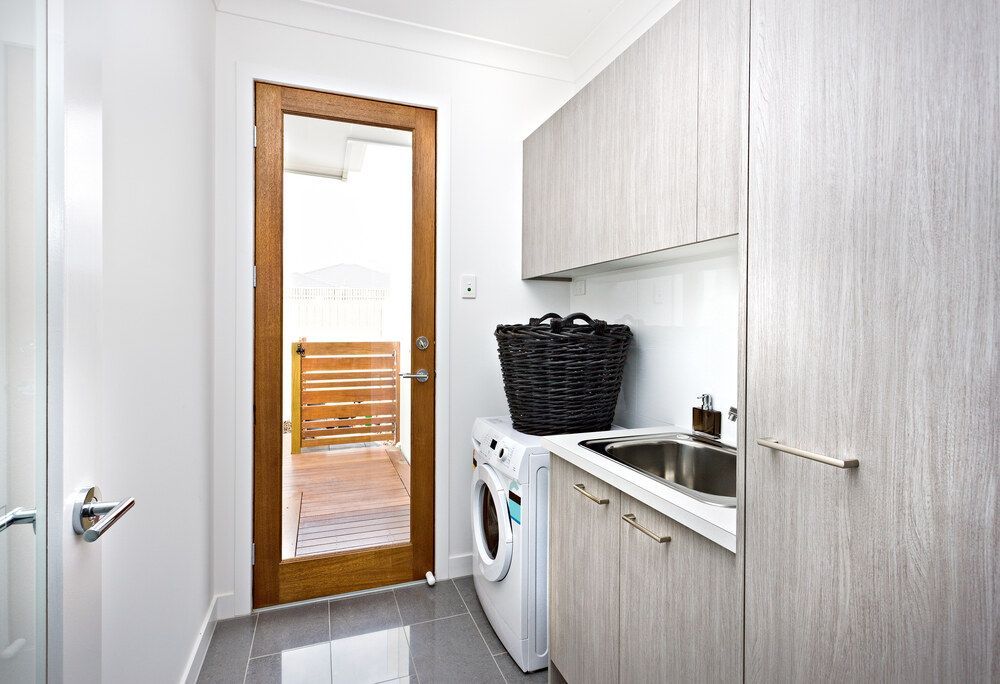 A Laundry Room With a Washer and Gray Cabinets — Bruce Smith Cabinets in Bray Park, NSW
