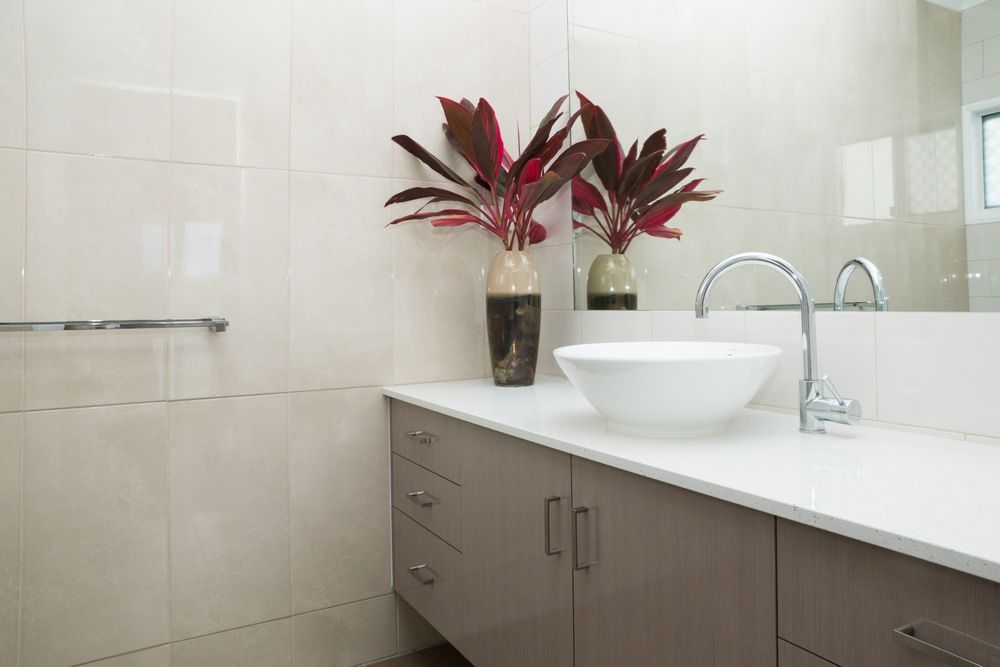 A Bathroom With a Sink and Two Vases of Flowers on the Counter — Bruce Smith Cabinets in Byron Bay, NSW