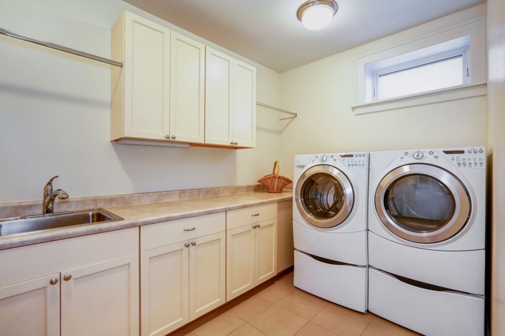 A Laundry Room With Two Washers and Dryers and a Sink — Bruce Smith Cabinets in Kingscliff, NSW