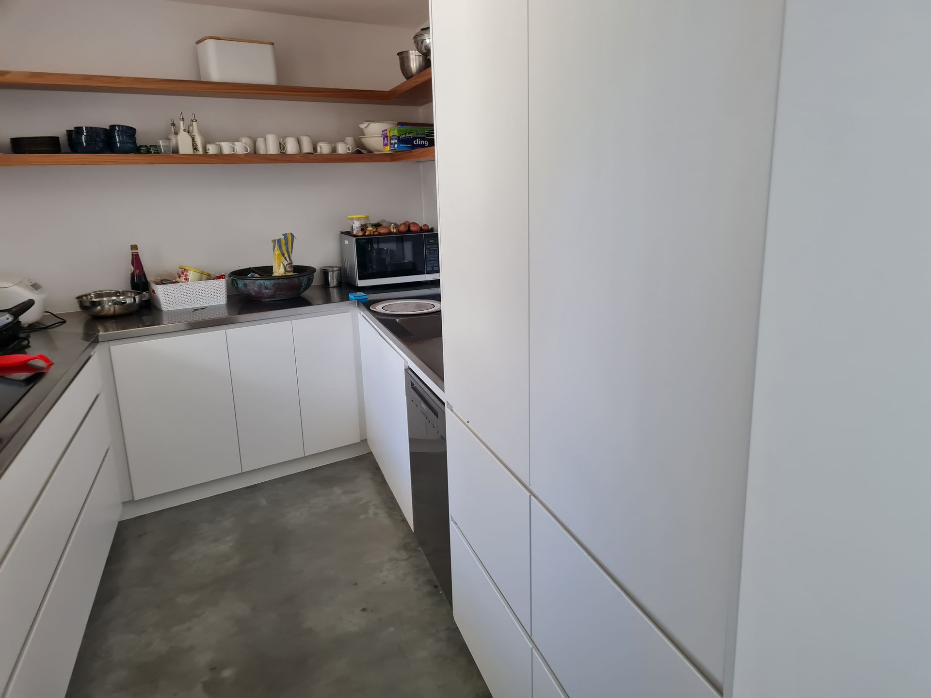 A kitchen with white cabinets , a sink , and a microwave.