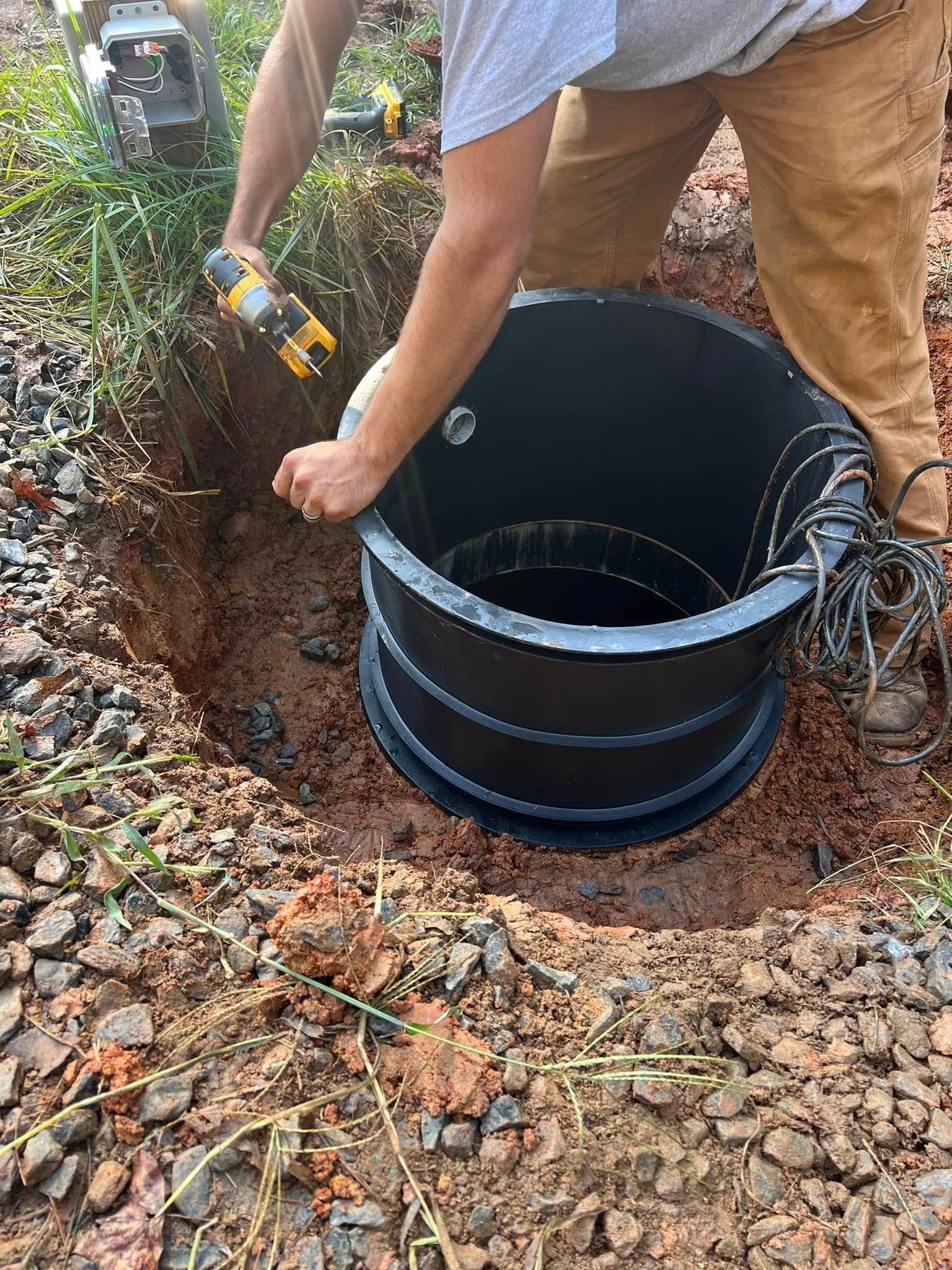 A man is digging a hole in the ground to install a septic tank.
