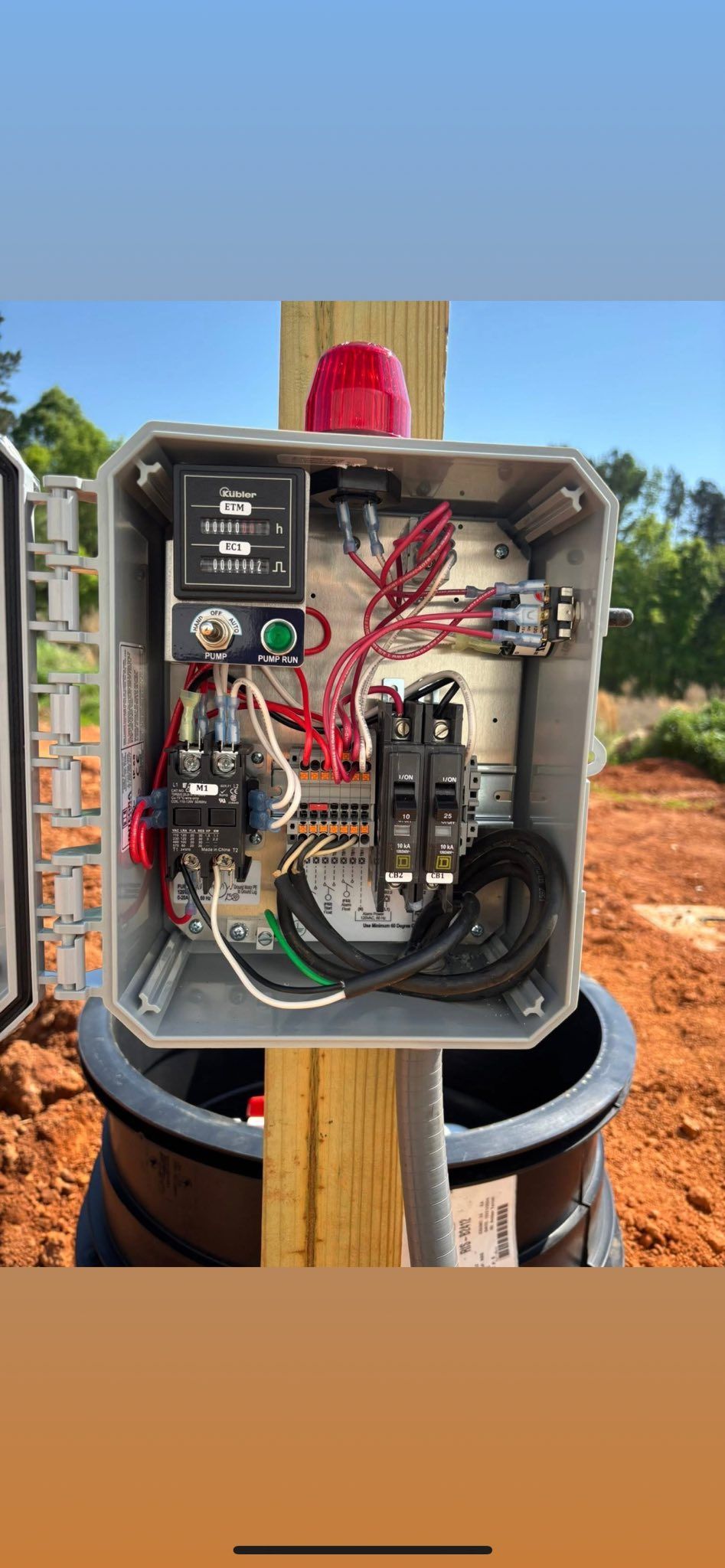 A box with a lot of wires in it is sitting on top of a wooden post.