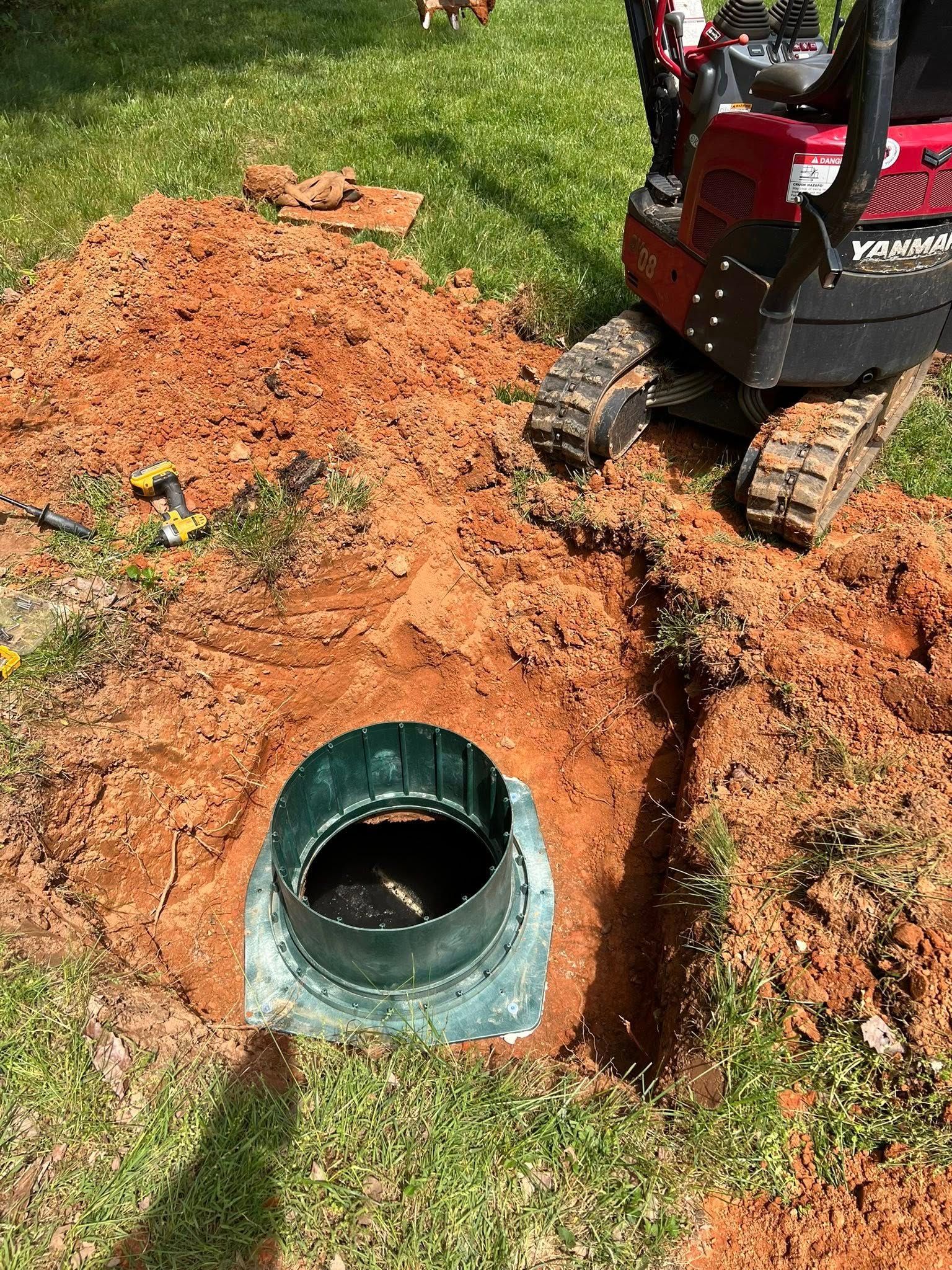 A small excavator is digging a hole in the ground to install a septic tank.