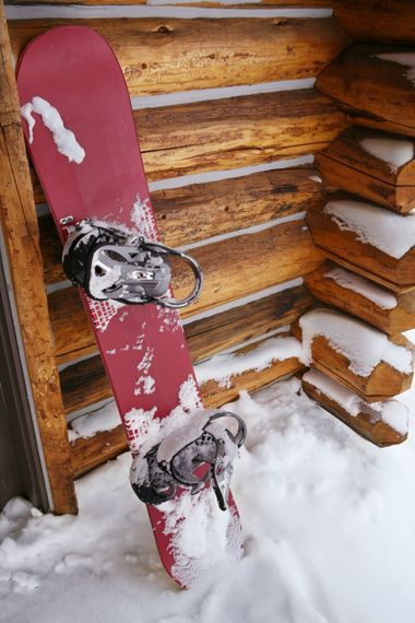 a snowboard is leaning against a wooden wall in the snow .