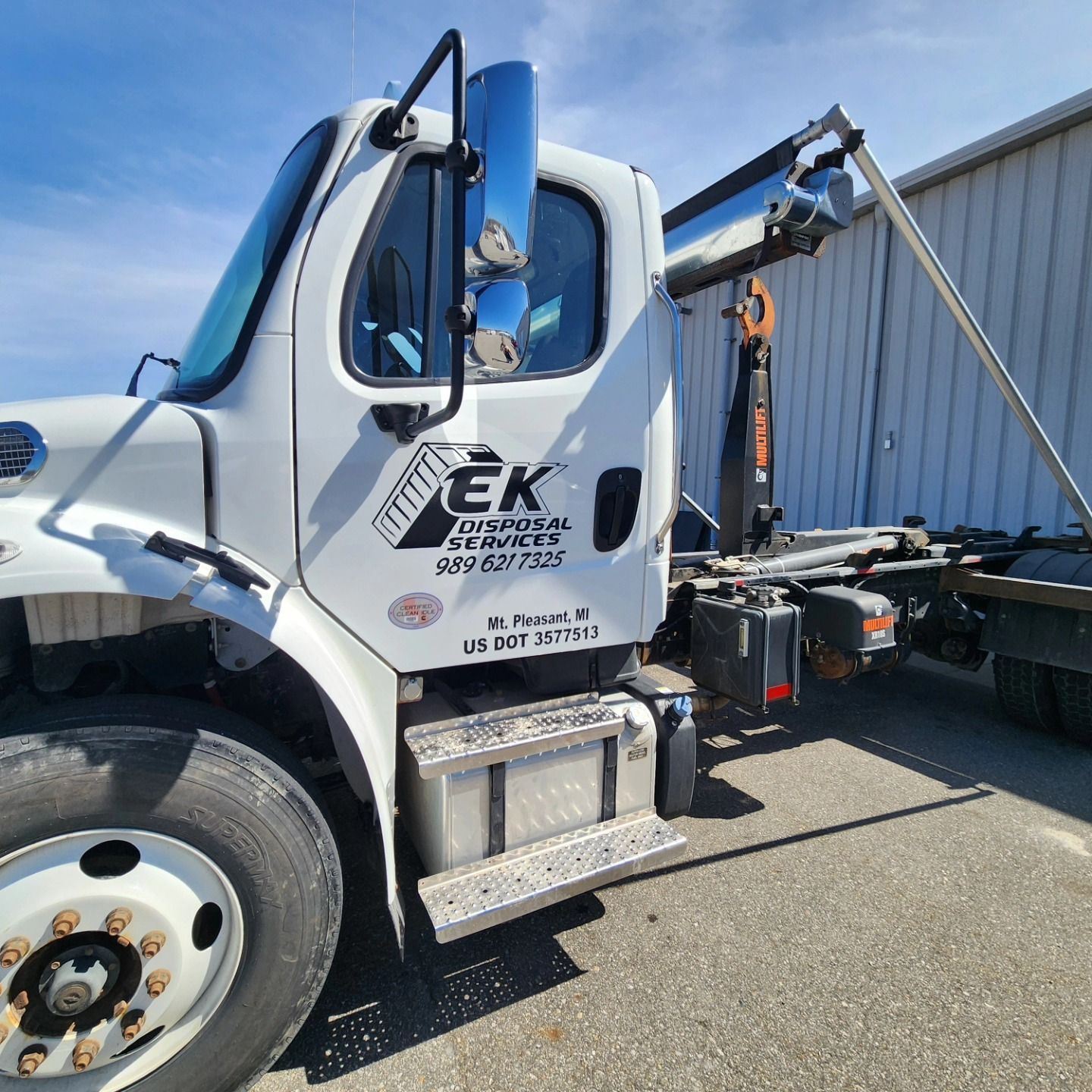 Four men loading construction debris into a dumpster in front of a house.