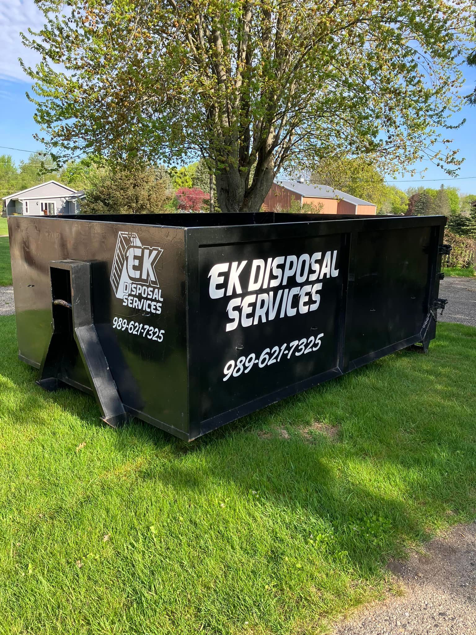 Black dumpster on grass with 