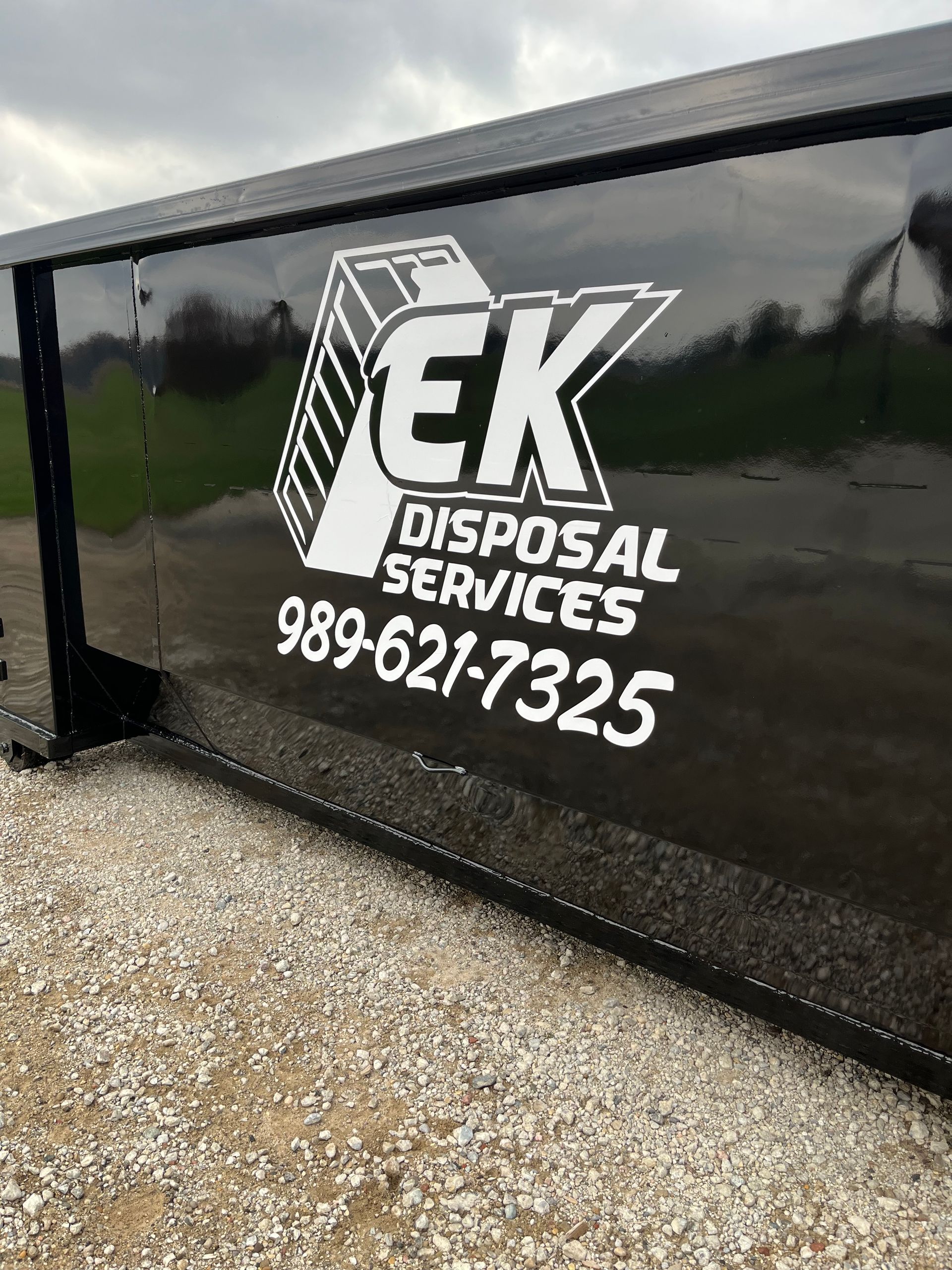 Construction workers around a yellow dumpster at a construction site. Wooden frames of houses in progress.