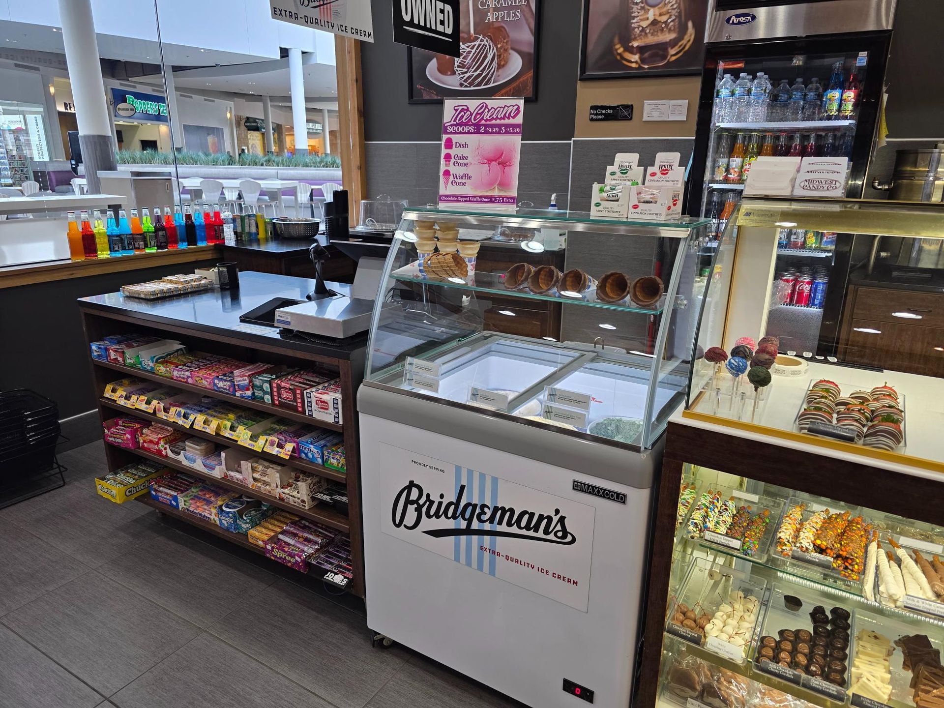 A shop interior with an ice cream display, shelves of candy, and refrigerated beverages.