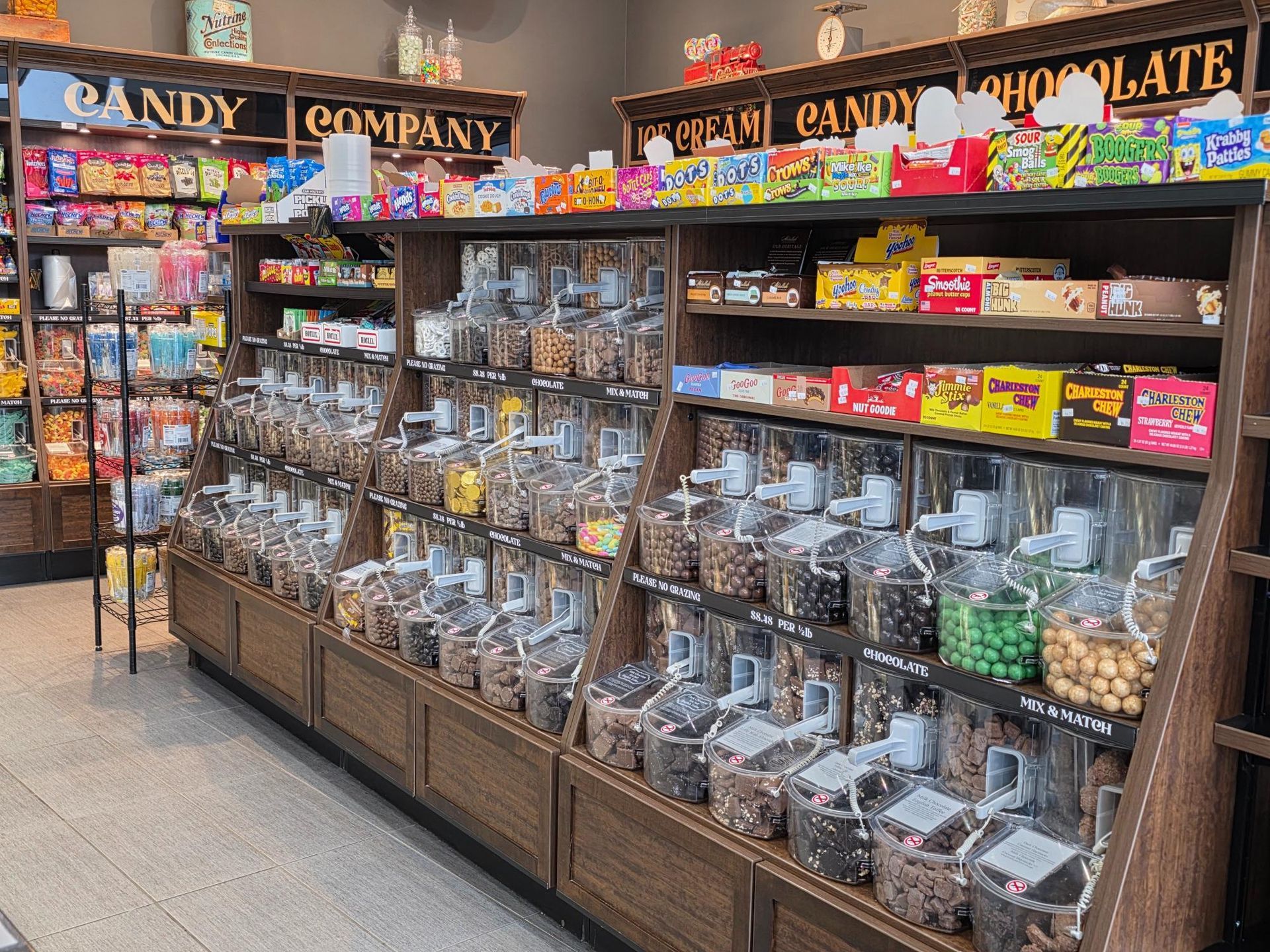 Candy store interior with wooden shelves filled with candy jars and packaged sweets.