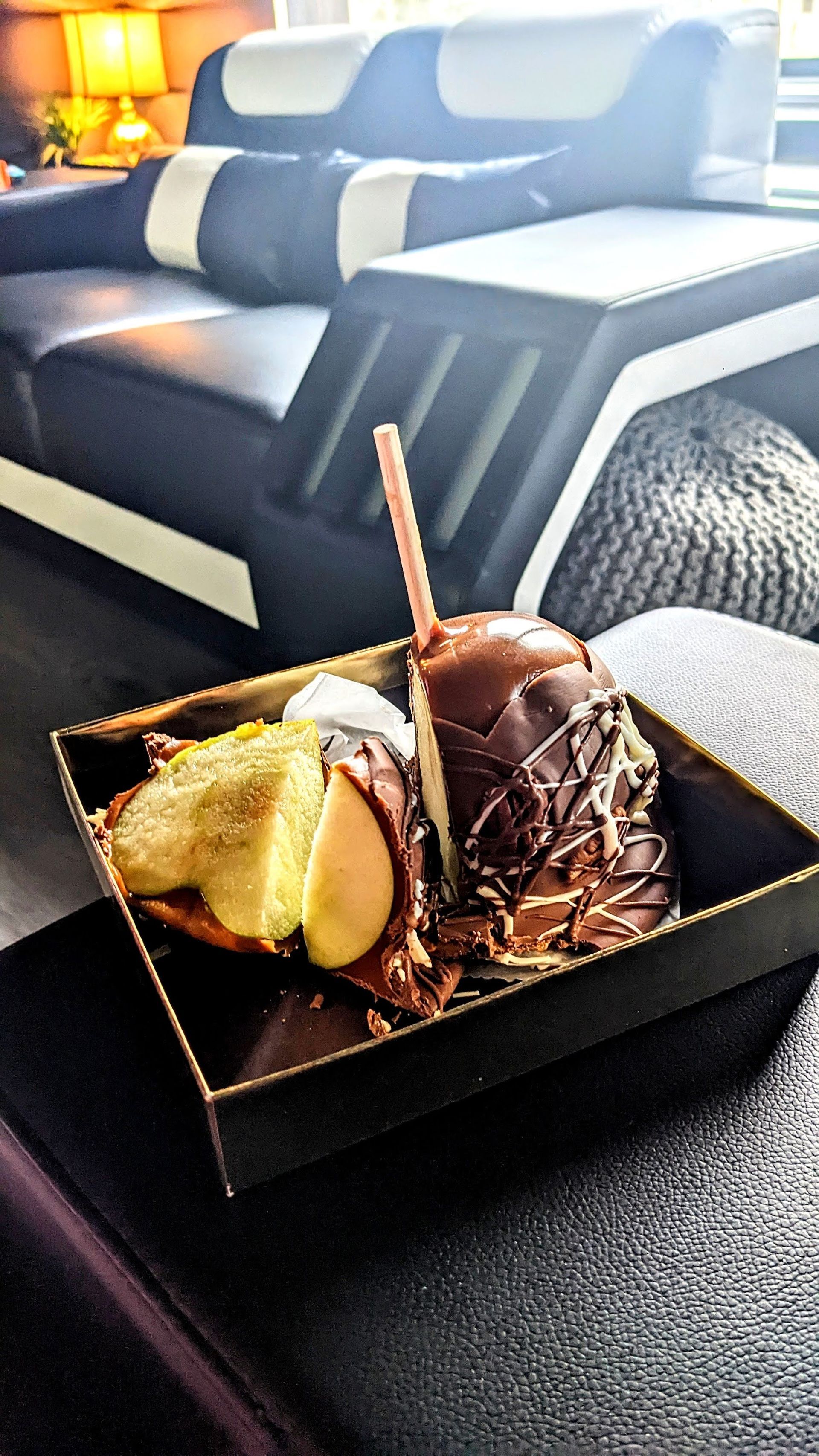 Chocolate-covered apples on a tray in front of a black and white couch.