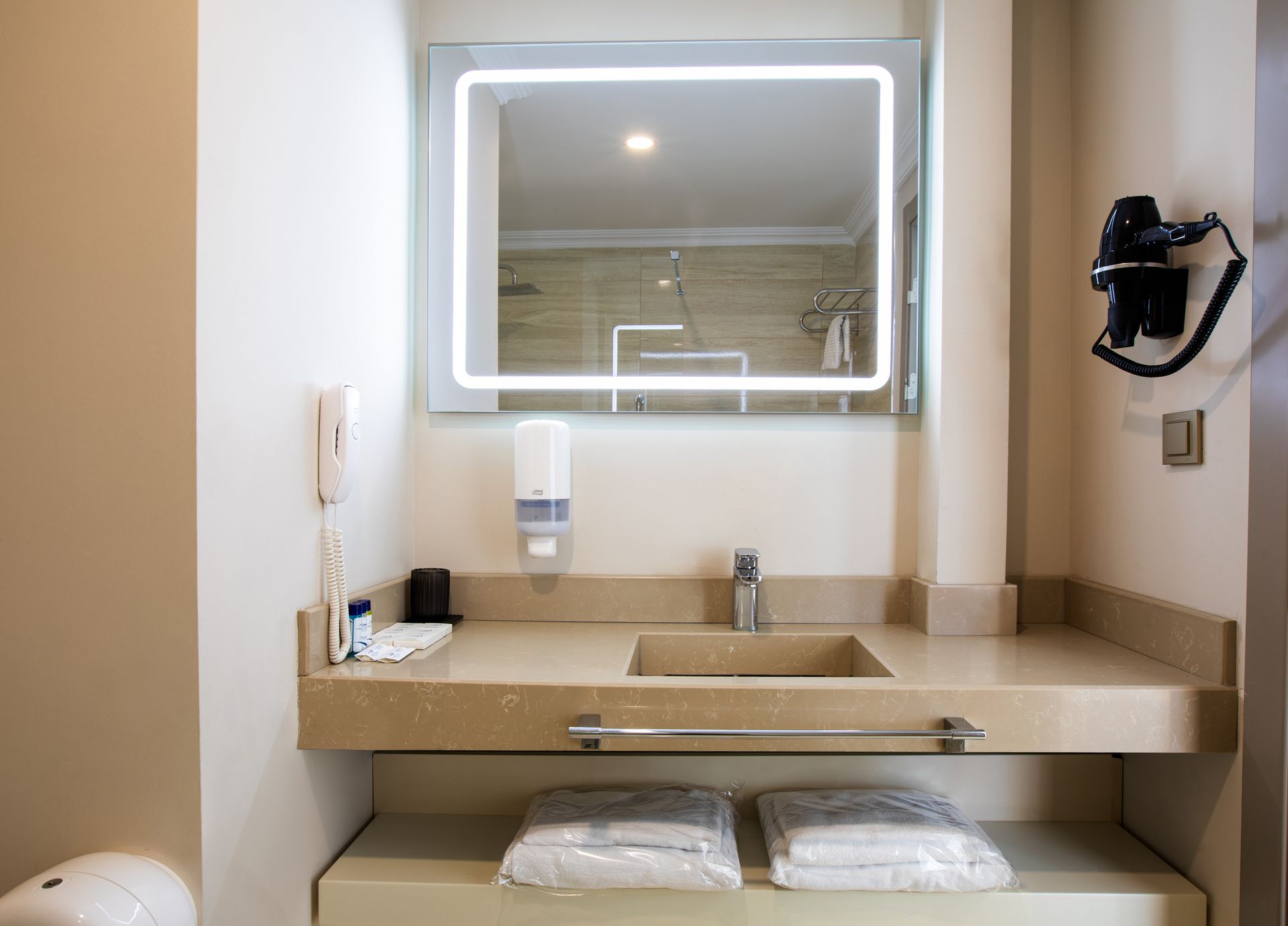 Lavabo, ayna ve saç kurutma makinesi içeren bir banyo.