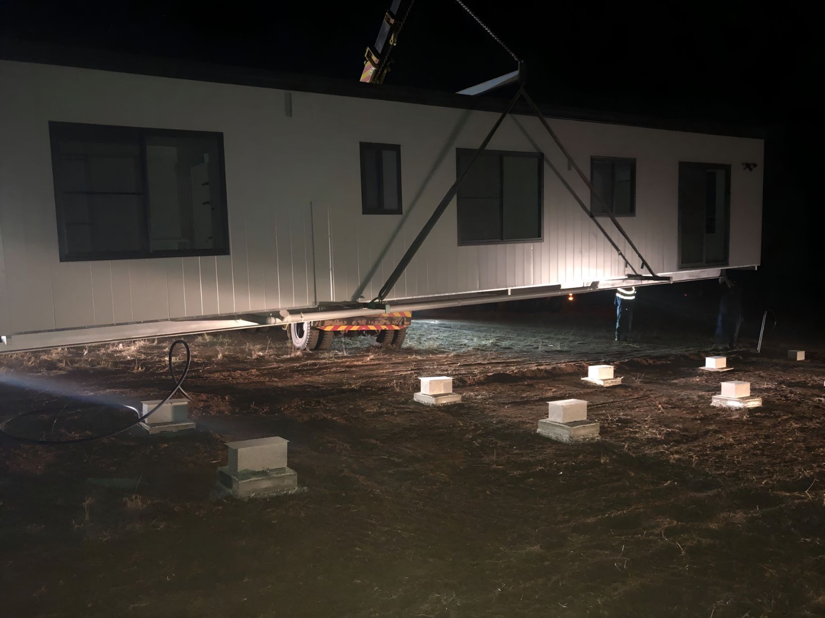 A Mobile Home is Being Lifted by a Crane at Night — OSM Transportables In Gunnedah, NSW