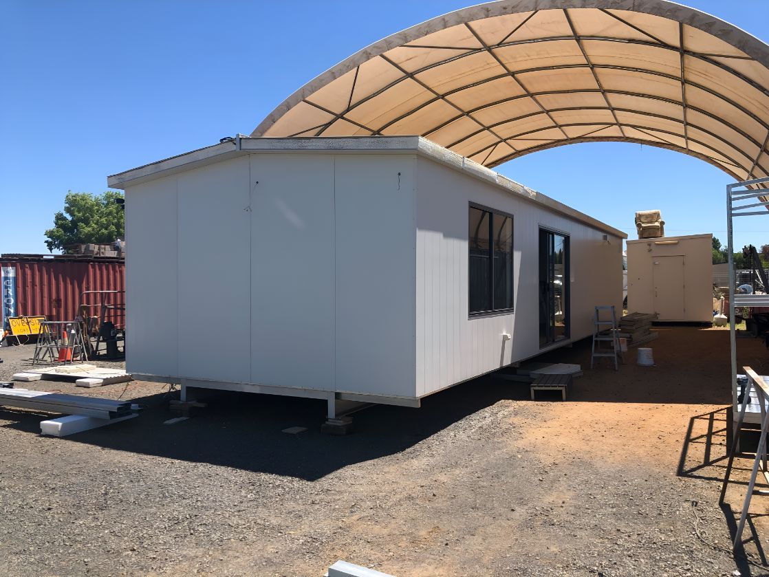 A White Trailer is Parked Under a Canopy in a Gravel Lot — OSM Transportables In Bourke, NSW