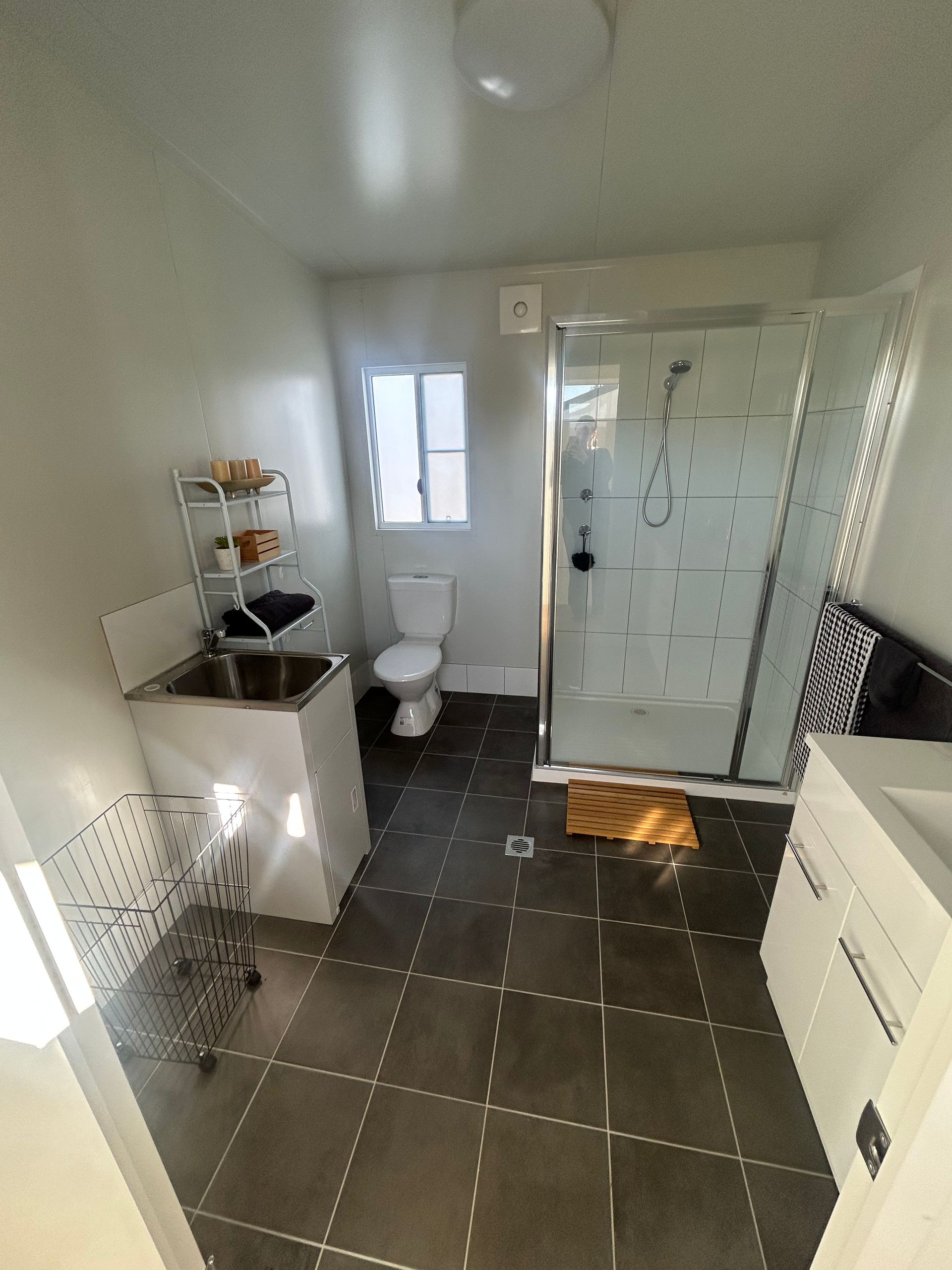 A Modern Bathroom With Grey Floor Tiles, a Glass Shower Stall — OSM Transportables In Dubbo, NSW