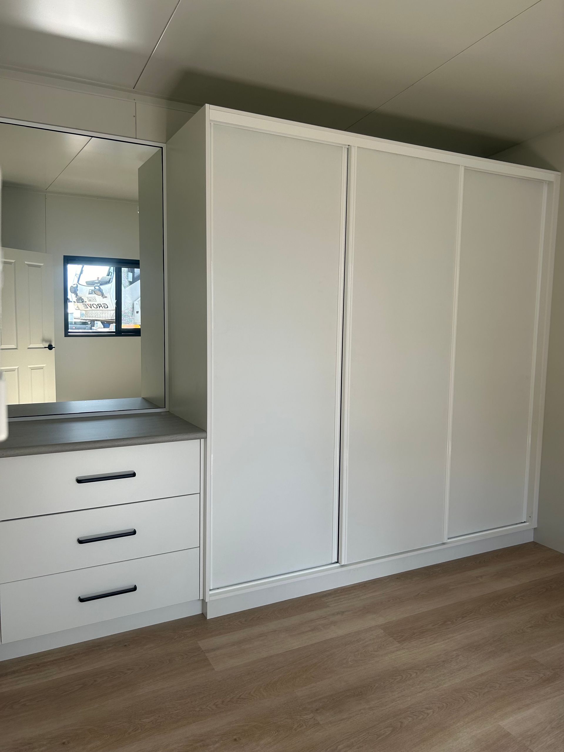A White Sliding-door Wardrobe With an Attached Three-drawer Vanity Unit — OSM Transportables In Dubbo, NSW