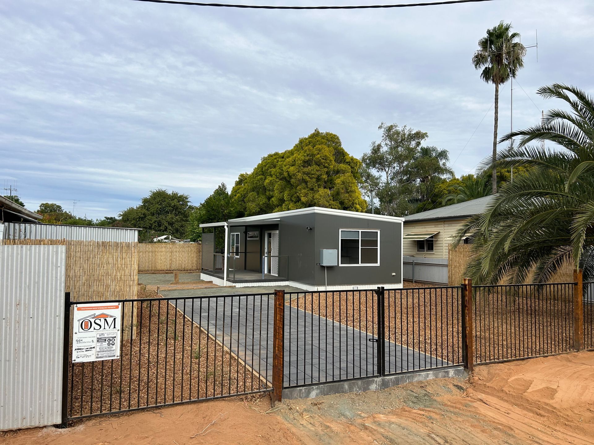 A Modern, Gray Prefabricated Home Sits Behind a Black Metal Fence — OSM Transportables In Dubbo, NSW