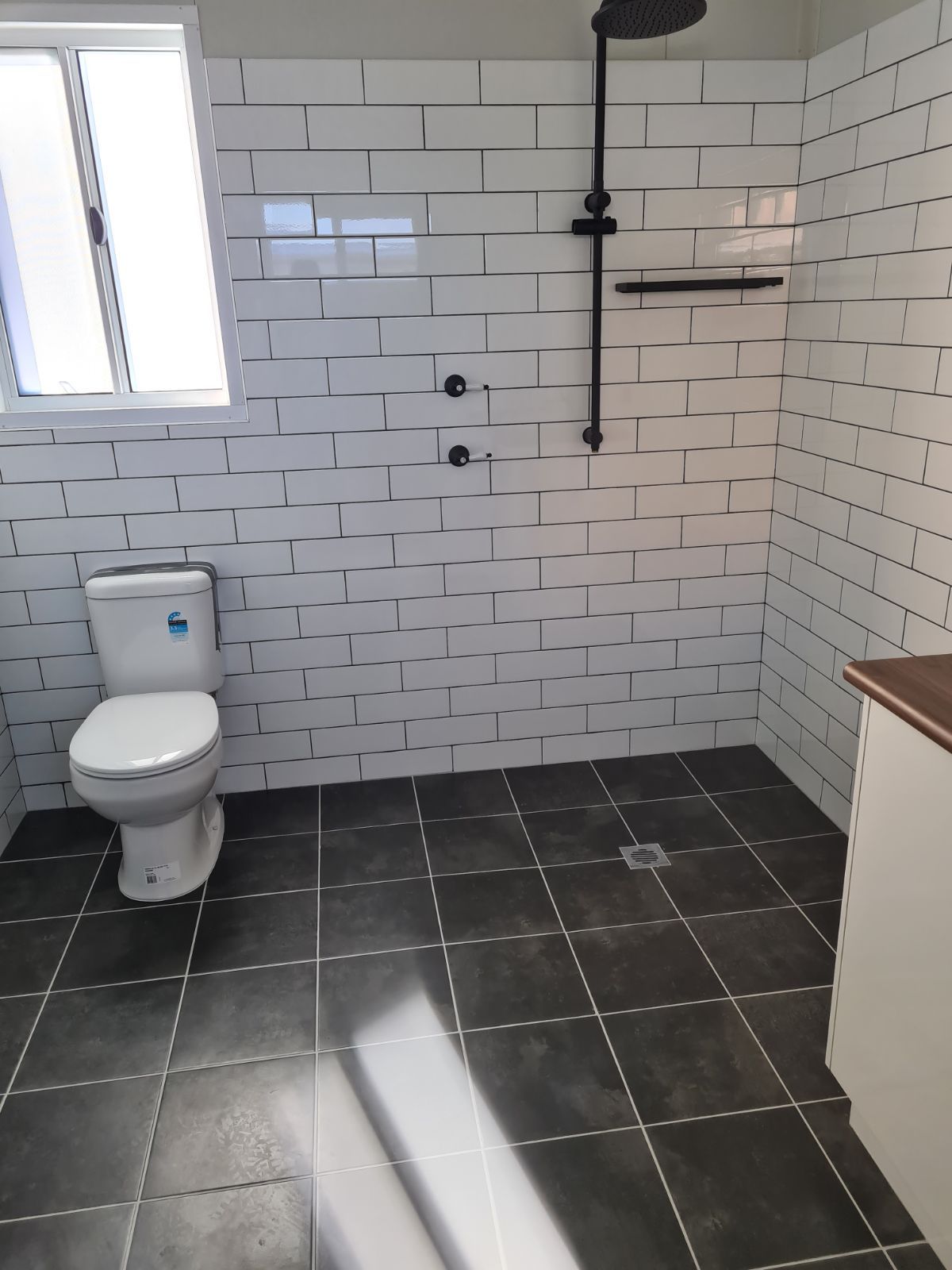 A Modern Bathroom Featuring a White Subway-tiled Walk-in Shower With Black Fixtures — OSM Transportables In Dubbo, NSW
