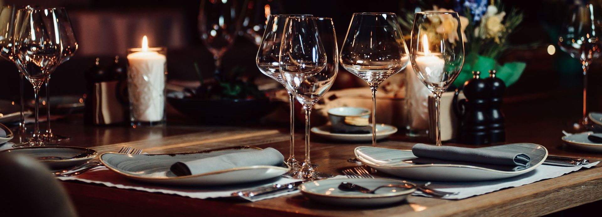Formal dining table set with glassware, candles, plates, and a floral arrangement.