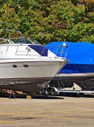 A boat is sitting on a trailer in a parking lot.
