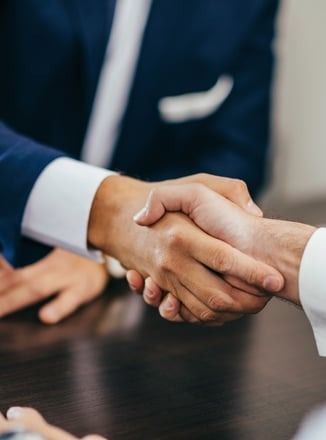 A man and a woman are shaking hands over a table.