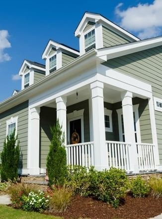 A house with a large porch and a blue sky in the background