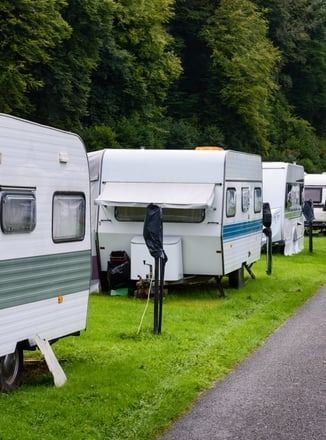 A row of camper trailers parked in a grassy field.