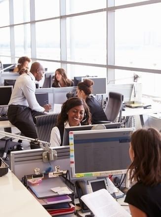 A group of people are sitting at desks in an office.