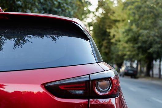 The back of a red car is parked on the side of the road.