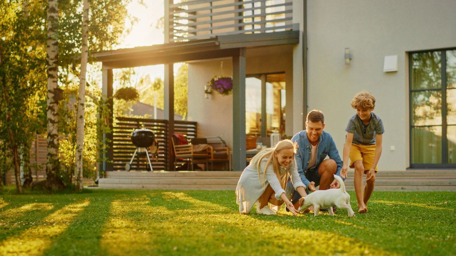 A family is playing with a puppy in their backyard.