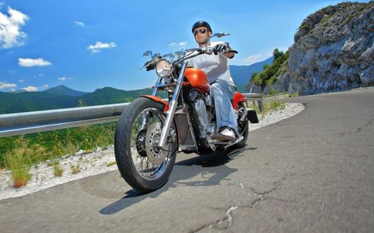 A man is riding a motorcycle down a mountain road.