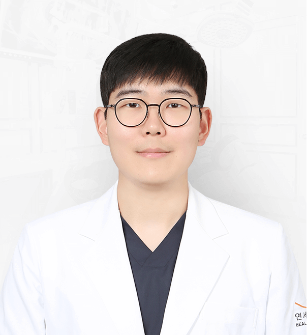 Young man in glasses and white coat, smiling at the camera.