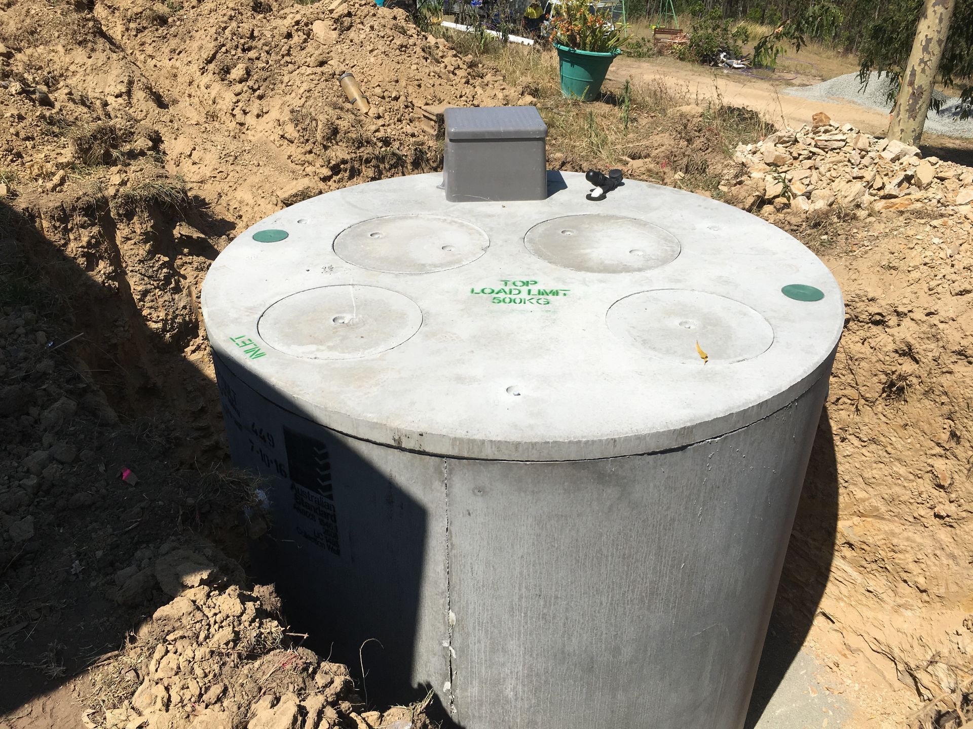 A Cylindrical Concrete Septic Tank with Four Access Lids and A Small Control Box — VR Marsden Plumbing in Red Rock, NSW