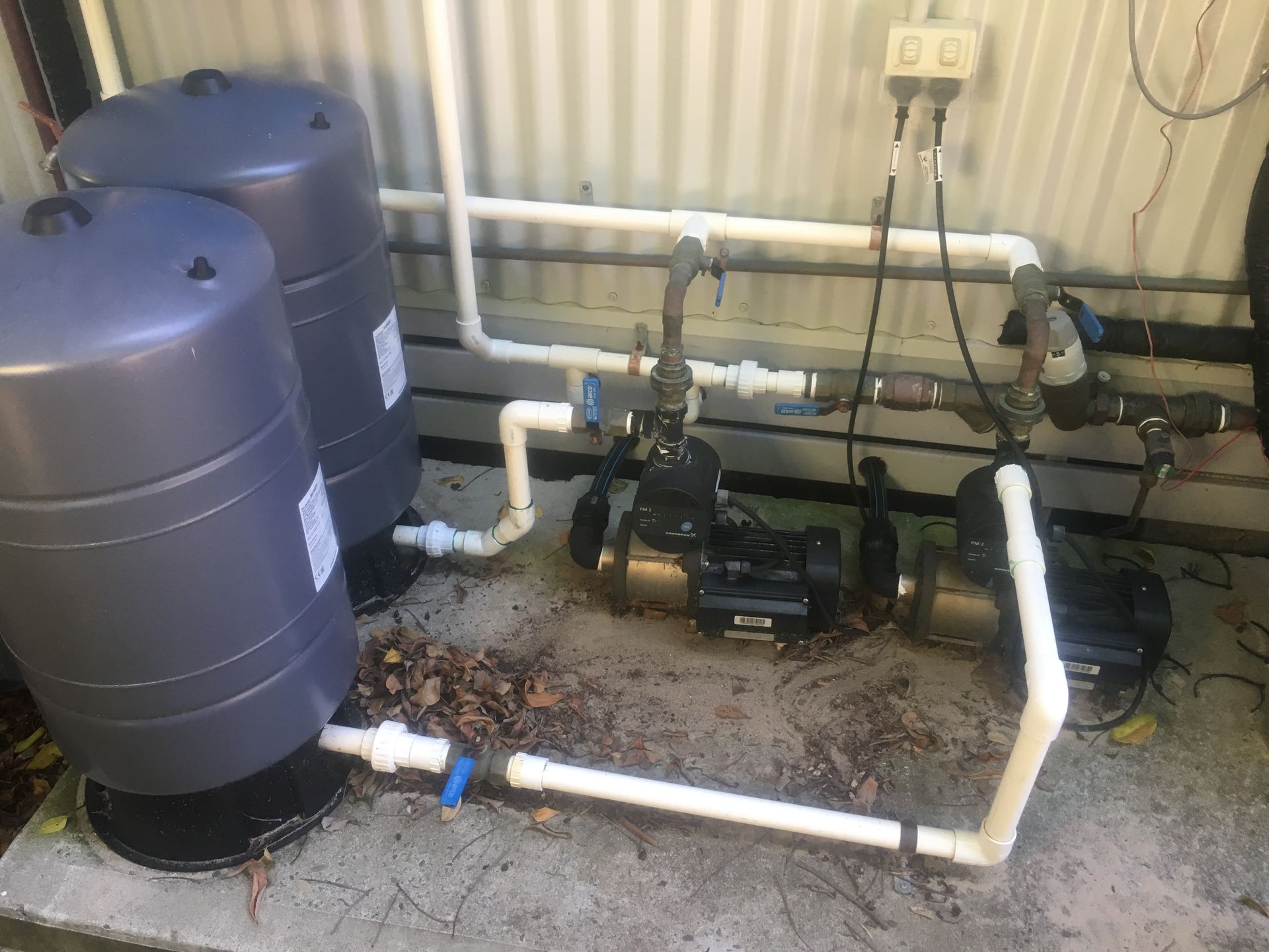 Water tanks and pumps, white pipes, grey tanks, electrical outlets on a concrete slab, outdoors— VR Marsden Plumbing in Red Rock, NSW