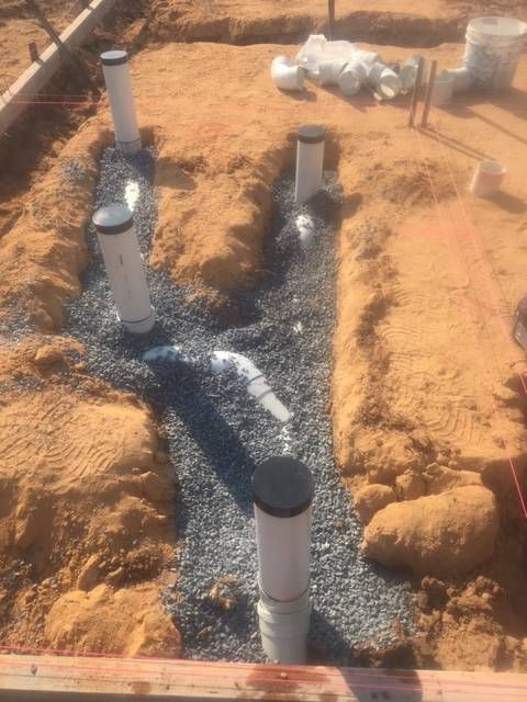 Pipes and gravel in trenches, likely for plumbing, within a construction site— VR Marsden Plumbing in Red Rock, NSW