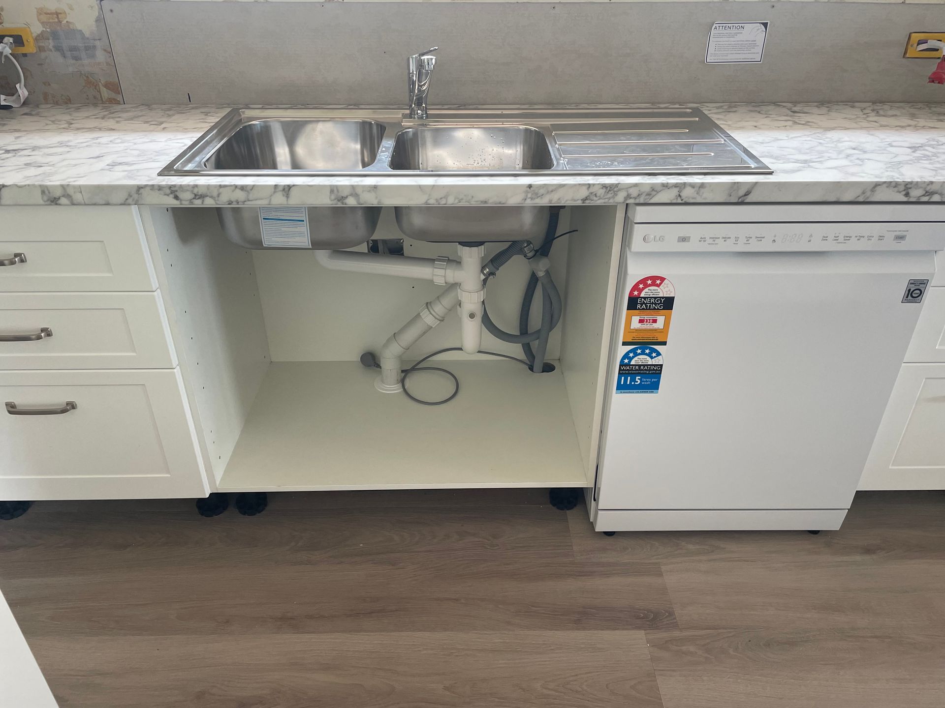 Kitchen sink and dishwasher in white cabinets, with plumbing visible below the sink— VR Marsden Plumbing in Red Rock, NSW