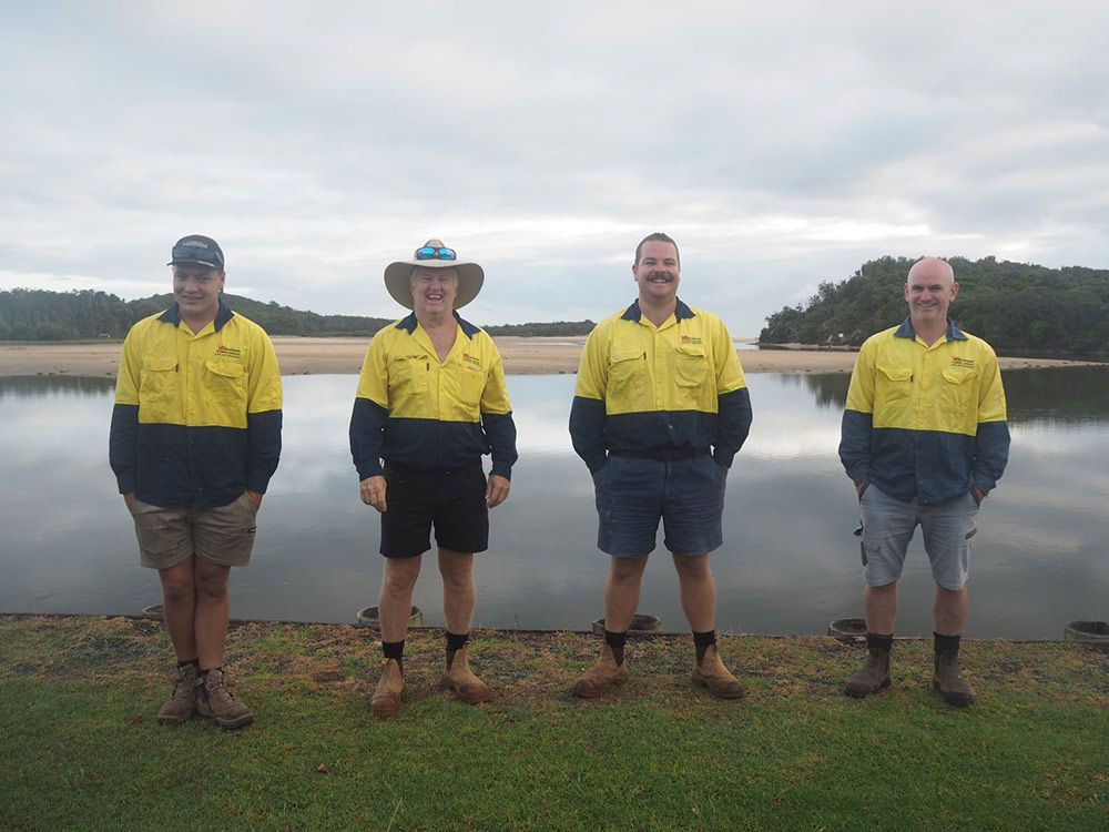 Four Men in Work Shirts Stand by Water, Smiling — VR Marsden Plumbing in Red Rock, NSW