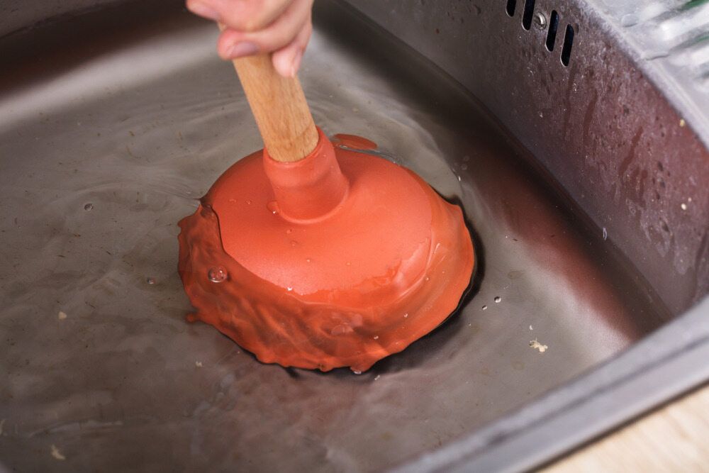 Plunger Being Used in a Stainless Steel Sink to Unclog It — VR Marsden Plumbing in Nana Glen, NSW