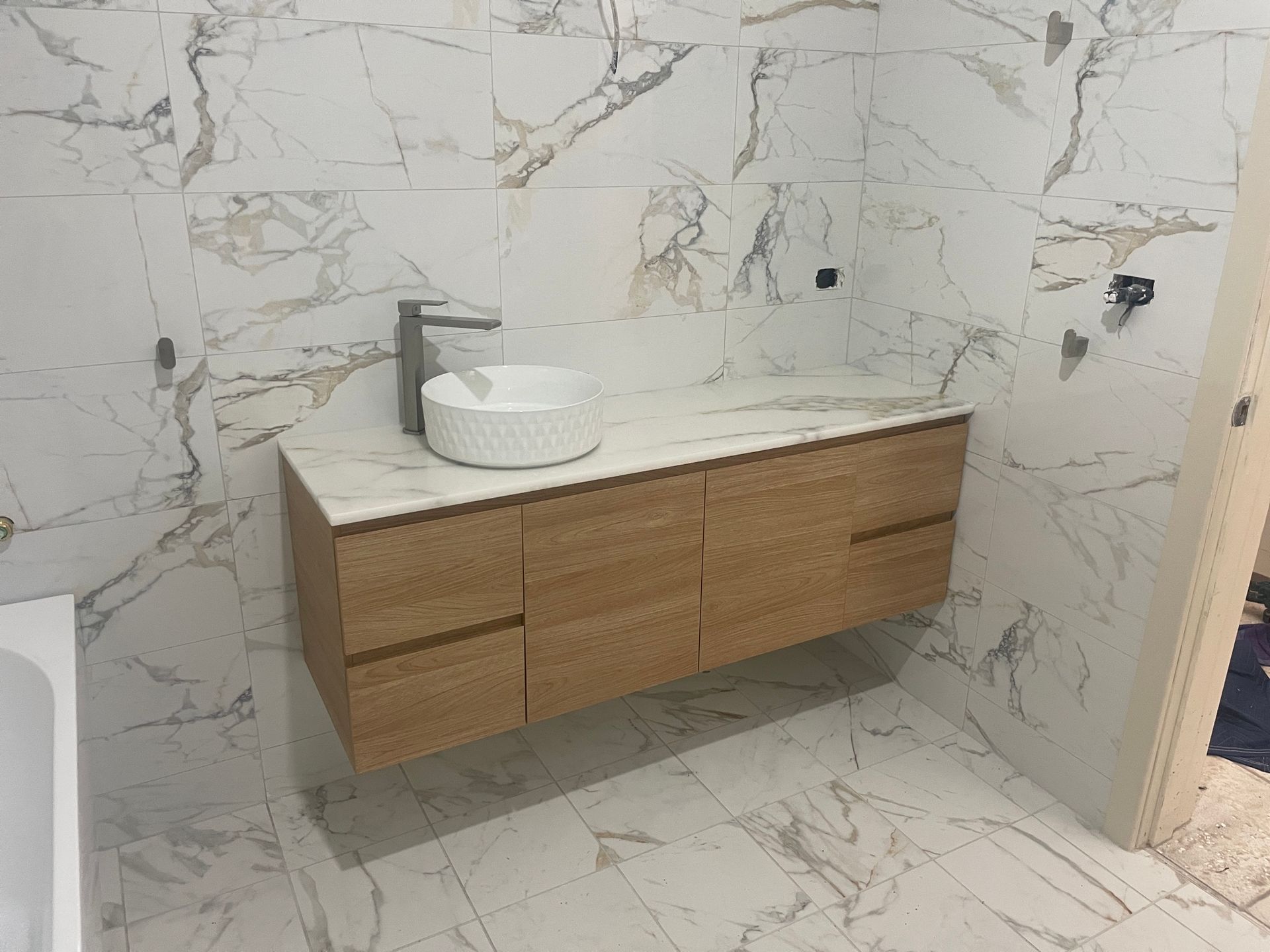 A bathroom vanity in a bathroom with marble tiles — VR Marsden Plumbing in Red Rock, NSW