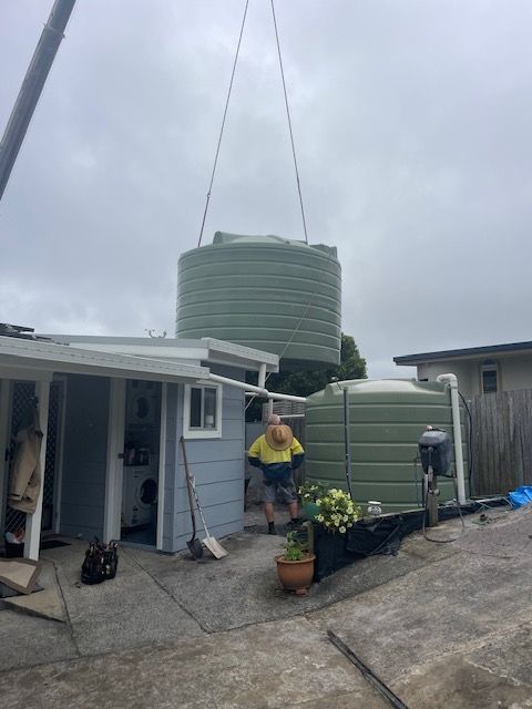 A Crane is carrying a large Green water tank — VR Marsden Plumbing in Red Rock, NSW