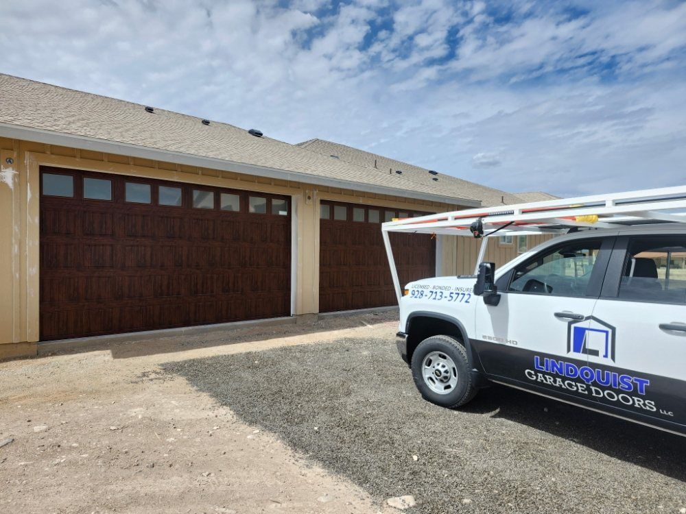 Two brown garage doors on a tan building. A white truck with