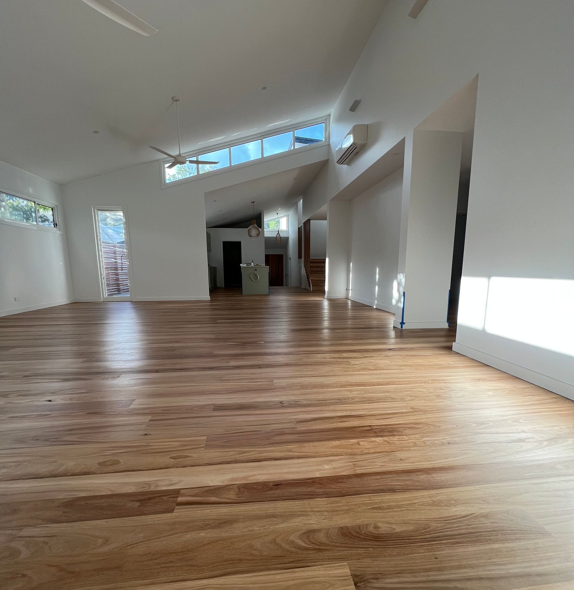 A Large Empty Room With Hardwood Floors and a Ceiling Fan — Hart Projects Wollongong In Dapto, NSW
