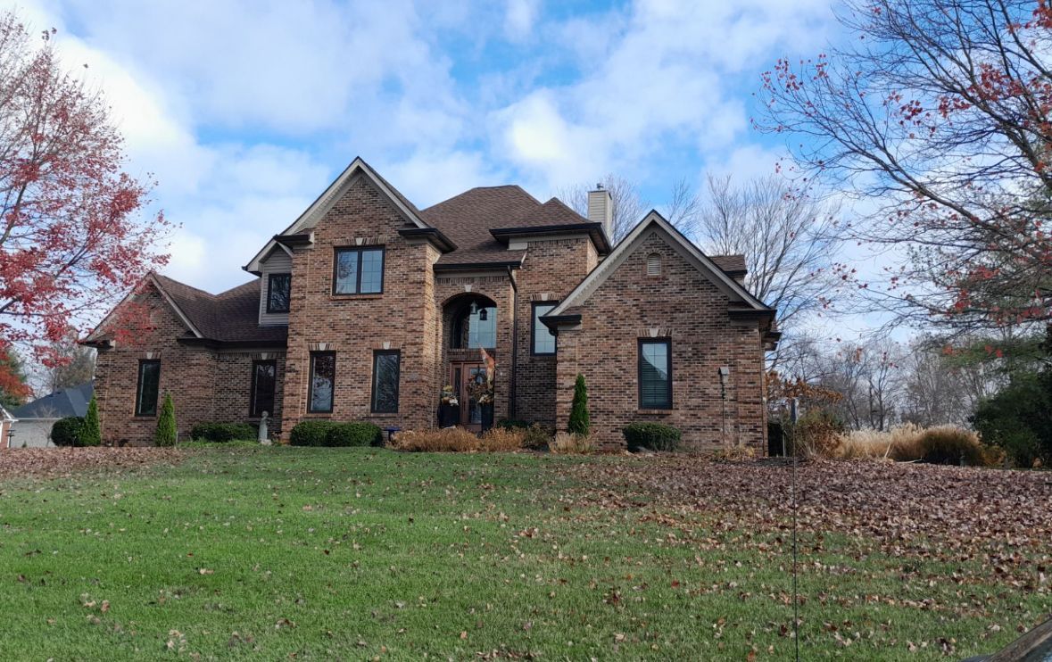 A large brick house sits on top of a lush green hillside – Palmyra, IN - Dunn Remodeling Company