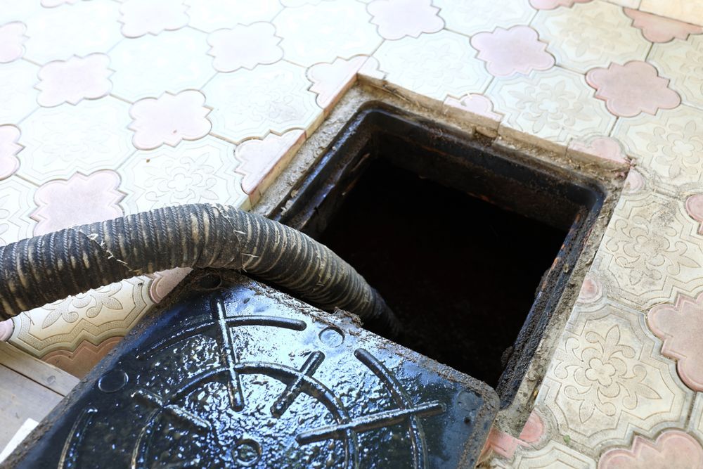 A Person Cleaning a Sludge With a Black Hose — Shreks Septic Services in Crows Nest, QLD