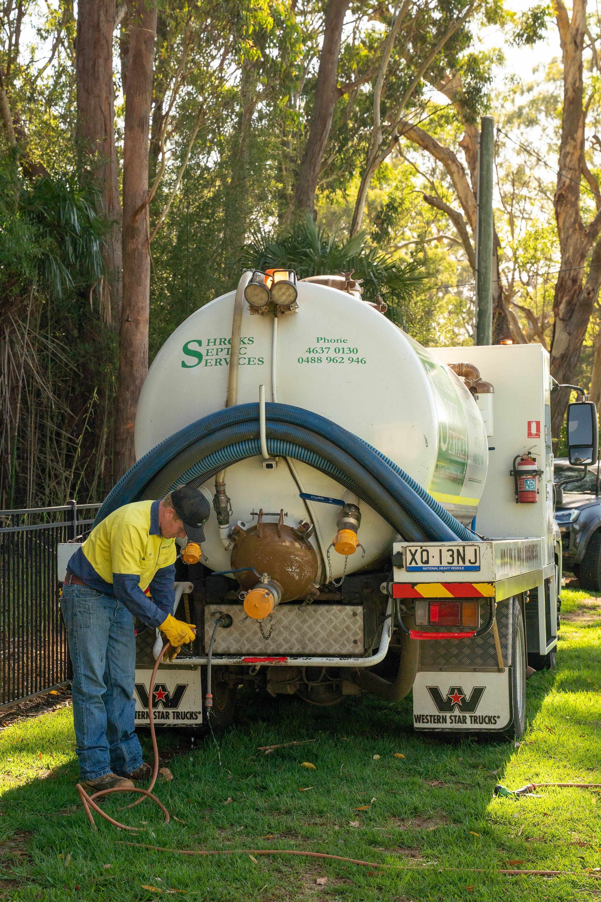 Worker in Yellow Shirt Cleaning a White Tank Truck — Shreks Septic Services in Gowrie Junction, QLD