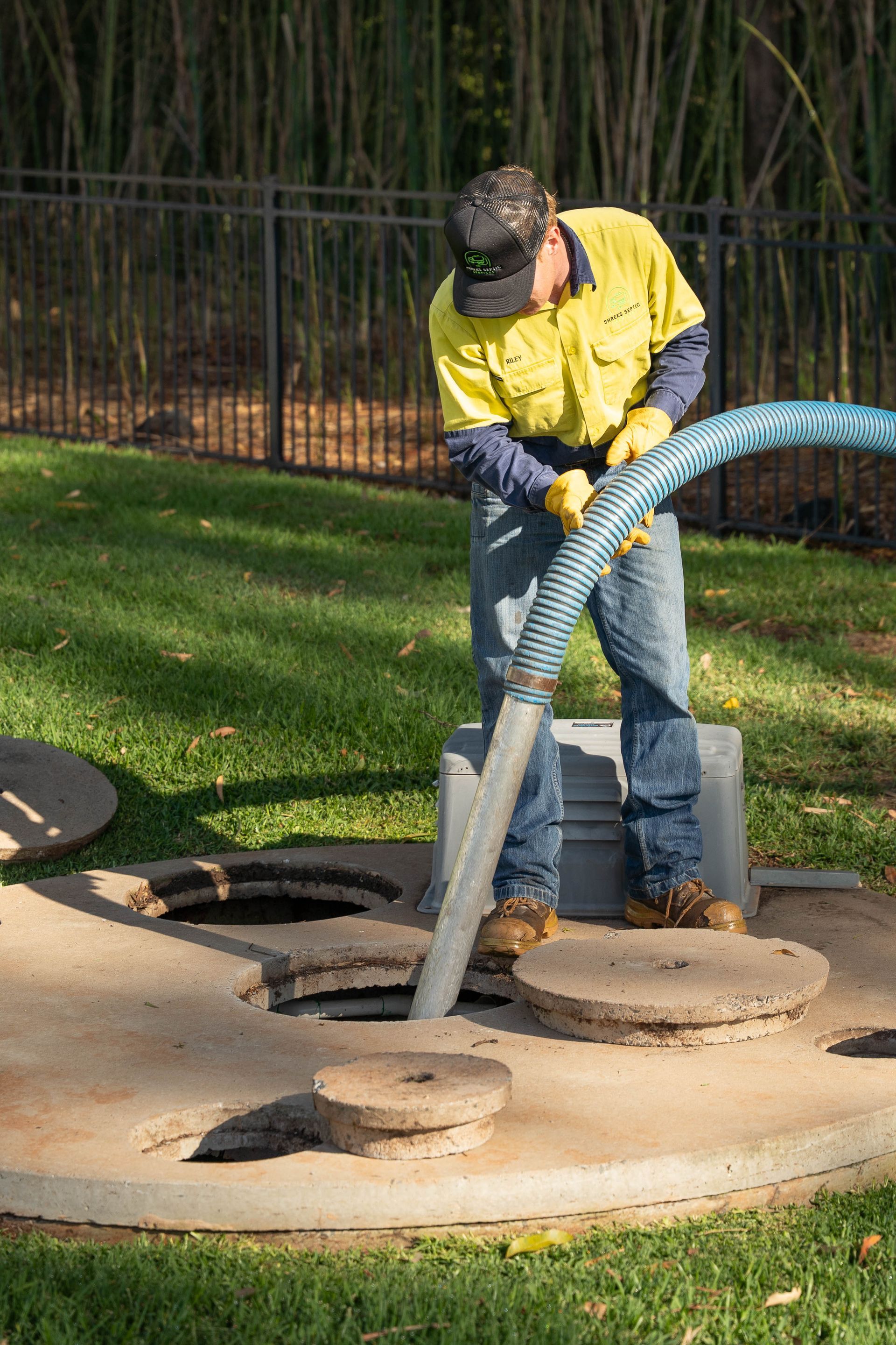 Worker in Yellow Jacket Cleaning a Manhole — Shreks Septic Services in Gowrie Junction, QLD