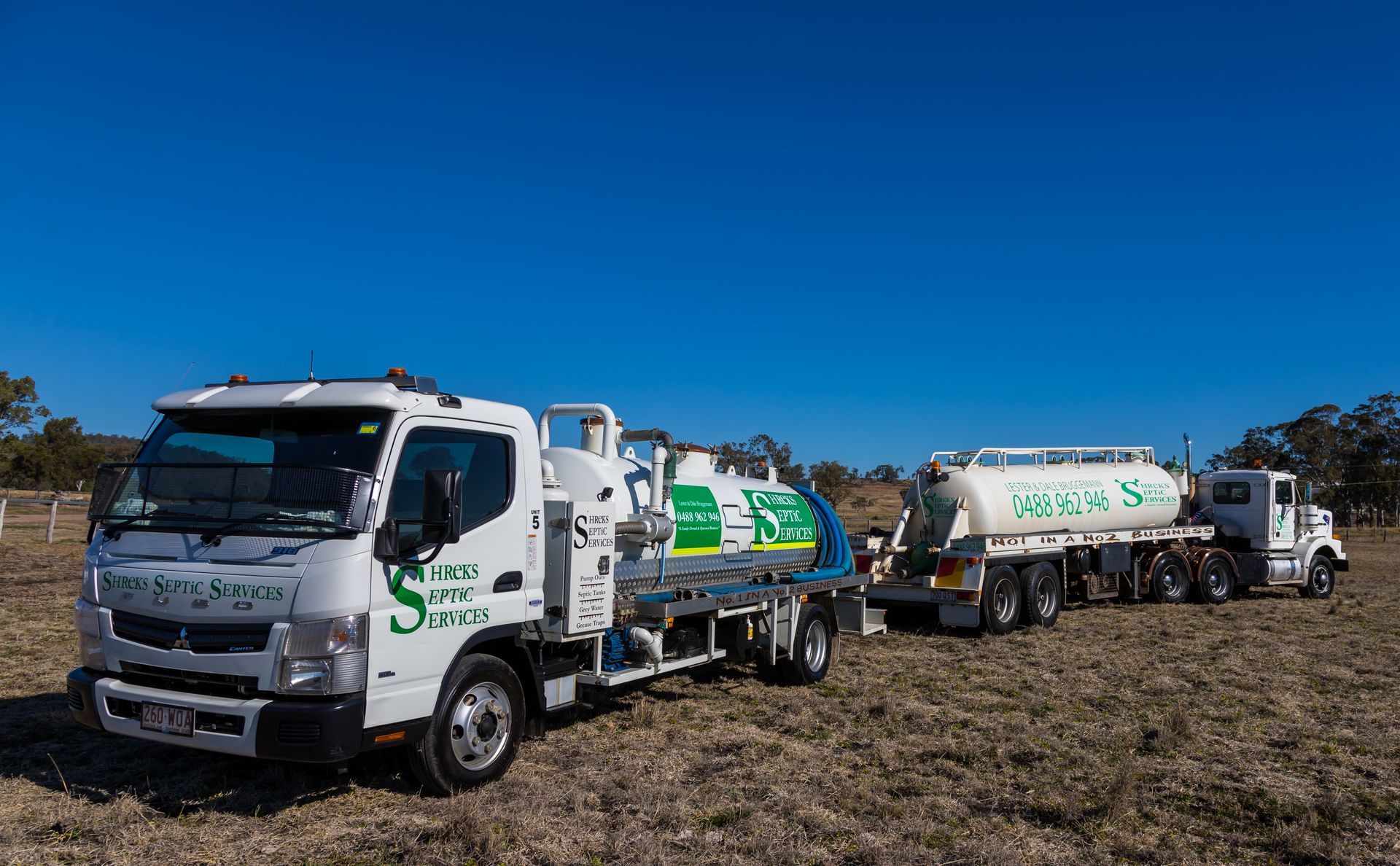 White Utility Trucks and Tank Trailers Lined Up in a Dry Field — Shreks Septic Services in Gowrie Junction, QLD