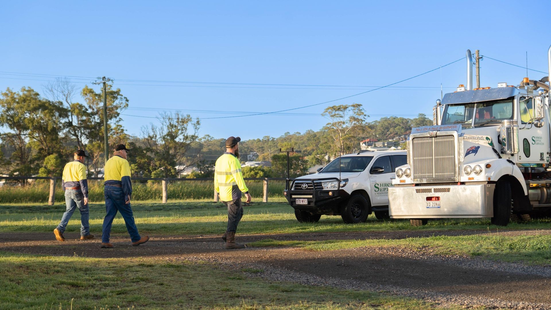 Three Workers in Yellow Shirts Stand Near a White Utility Truck — Shreks Septic Services in Crows Nest, QLD