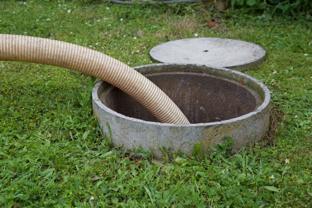 Gray Hose Inserted Into a Round Concrete Ground Drain — Shreks Septic Services in Cambooya, QLD