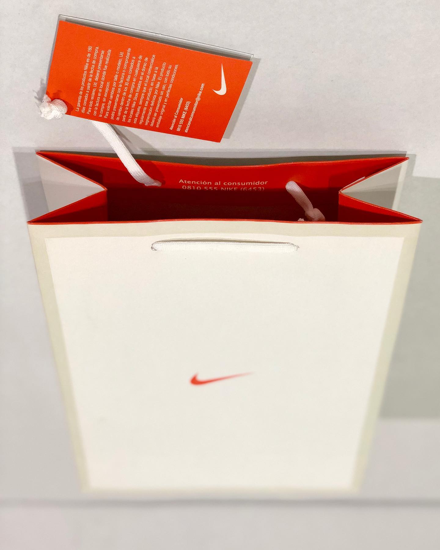 Una bolsa Nike blanca con una etiqueta roja adherida.